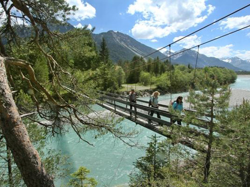 Drei Menschen auf einer Hängebrücke über dem Lech.