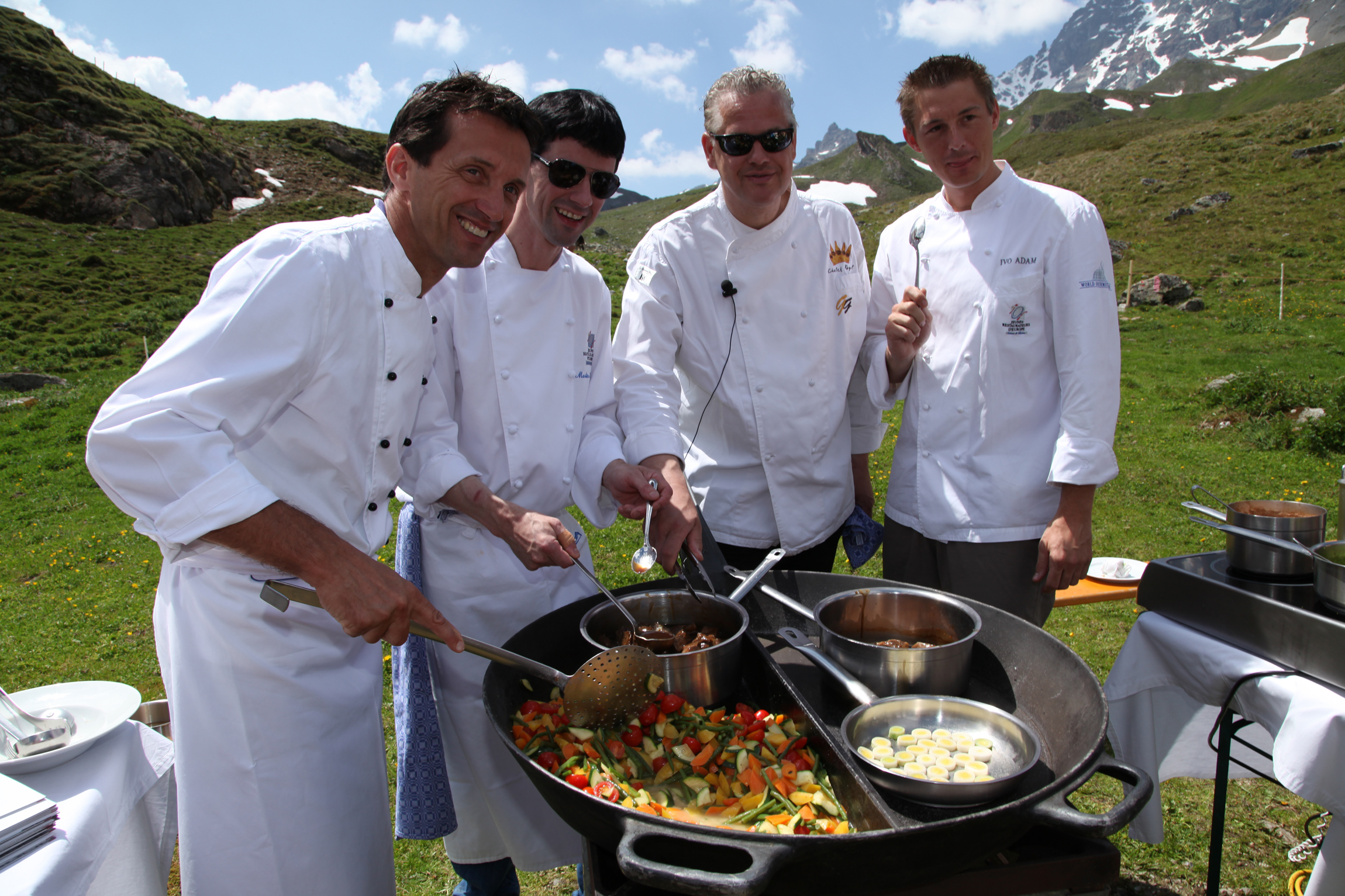 Vier Köche auf der Alm mit einer großen Pfanne.