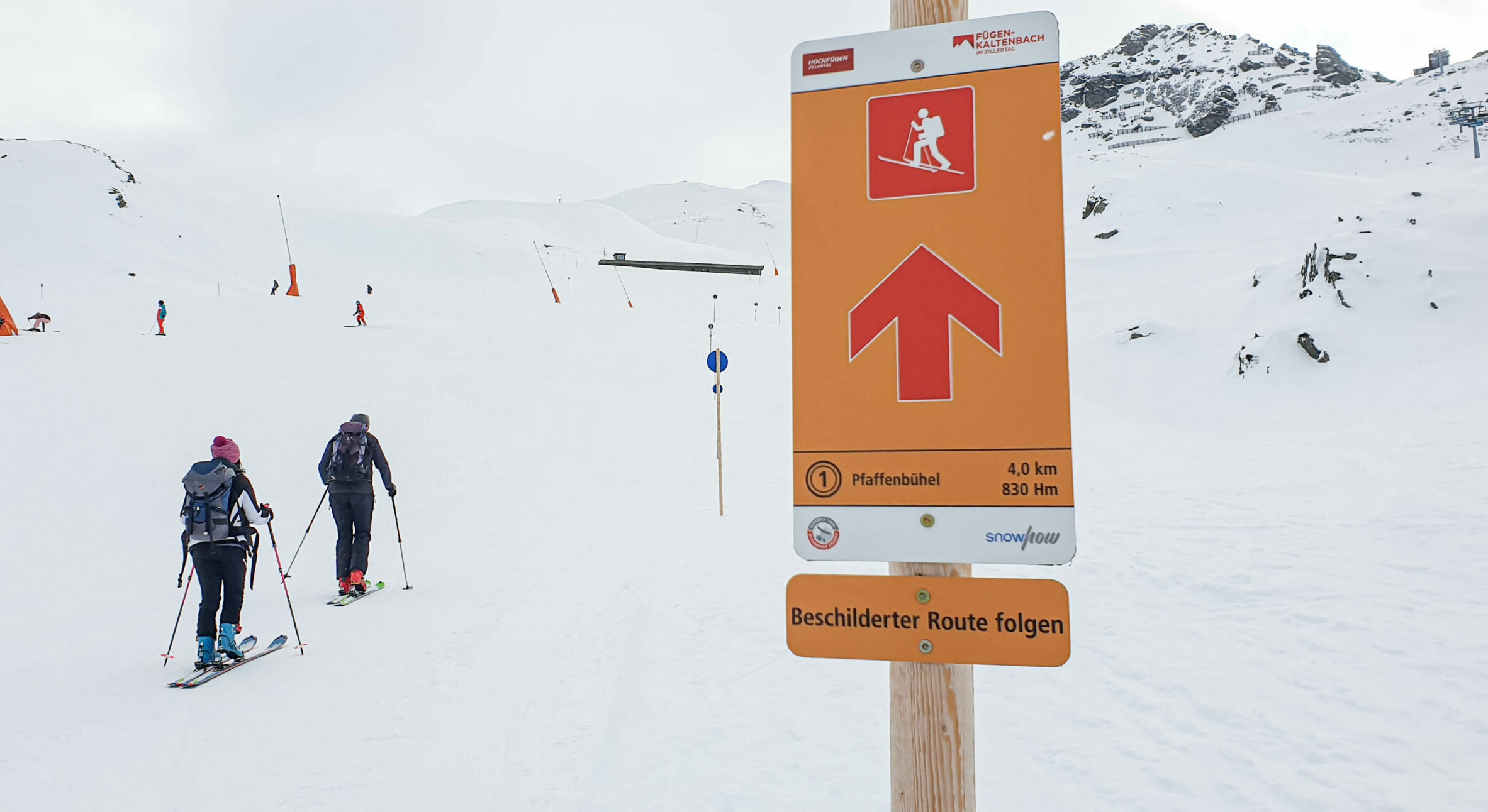 Tourengeher auf dem Berg, daneben ist ein Infoschild